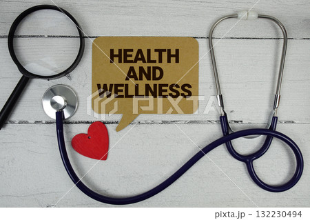 Health And Wellness text with Red heart, Magnifying glass and Medical Stethoscope on wooden background 132230494