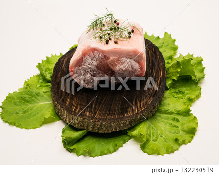 Piece of frozen meat, from which blows frosty freshness and cold. The meat lies on the leaves of fresh, green lettuce. Close-up Piece of frozen meat, from which blows frosty freshness and cold. The meat lies on the leaves of fresh, green lettuce. Close-up 132230519