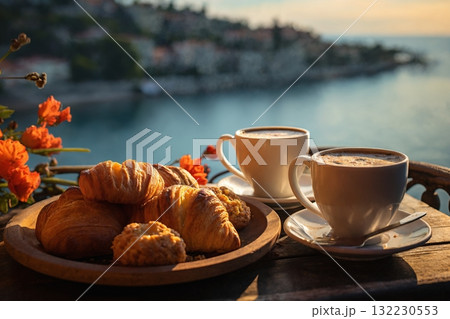 cup of coffee and french croissant on table, balcony with view of beautiful landscape, still life, sea and mountains, resort town, sunset 132230553