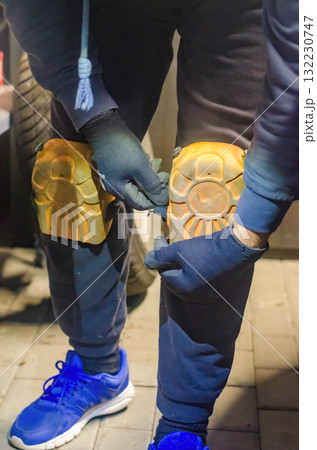 Worker Adjusting Protective Knee Pads Before Manual Garage or Construction Work 132230747