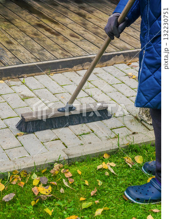 Person Sweeping Wet Pavement and Fallen Leaves with Large Outdoor Broom 132230751