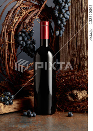 Bottle of red wine against the backdrop of an old weathered board, dried vine, and grapes. Bottle of red wine against the backdrop of an old weathered board, dried vine, and grapes. 132230862