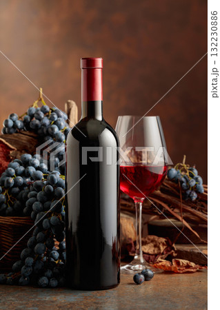 Bottle of red wine with blue grapes on a brown background. 132230886