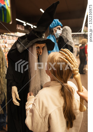 A child looks at a witch in a hat in a store for halloween 132230975