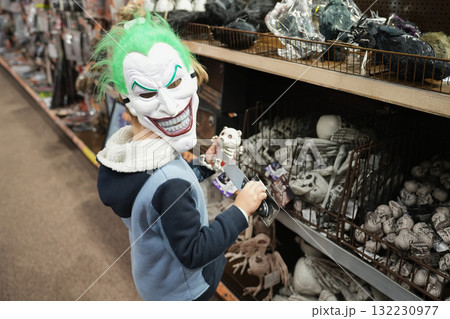 A child wearing a zombie mask chooses Halloween toys at a shop 132230977