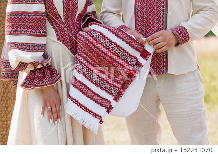 Authentic Ukrainian Couple in Traditional Vyshyvanka Embroidery Holding Cloth, Beige Linen, Red Accents, Cultural Heritage, Folk Costume, Close-Up Shot. Authentic Ukrainian Couple in Traditional Vyshyvanka Embroidery Holding Cloth, Beige Linen, Red Accents, Cultural Heritage, Folk Costume, Close-Up Shot. 132231070