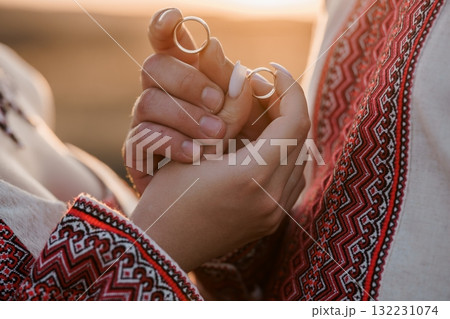 Romantic Wedding Rings Exchange Ceremony in Traditional Ukrainian Embroidered Clothing, Golden Light, Couple's Hands, Love, Commitment, Cultural Heritage. 132231074
