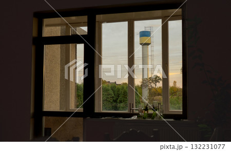 Window View of Water Tower at Sunset: Rustic Interior, Golden Light, Autumnal Trees, Nostalgic Atmosphere, Concrete Texture, Still Life Composition. Window View of Water Tower at Sunset: Rustic Interior, Golden Light, Autumnal Trees, Nostalgic Atmosphere, Concrete Texture, Still Life Composition. 132231077