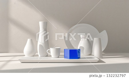 A white table with a blue object on it and a few white vases 132232797