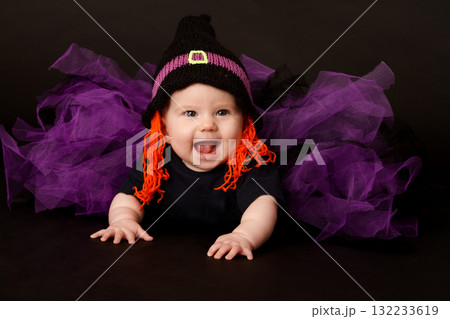 Smiling baby in Halloween witch costume with purple tulle skirt and orange yarn hair 132233619