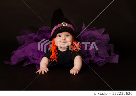 Smiling baby in Halloween witch costume with purple tulle skirt and orange yarn hair 132233626