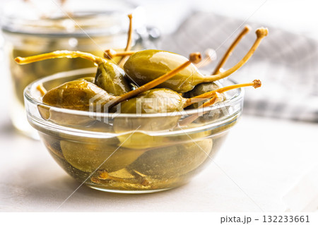 Pickled capers berries in bowl on white table Pickled capers berries in bowl on white table 132233661