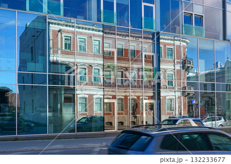 Historic building reflected in modern glass facade on city street in Liepaja, architecture contrast 132233677