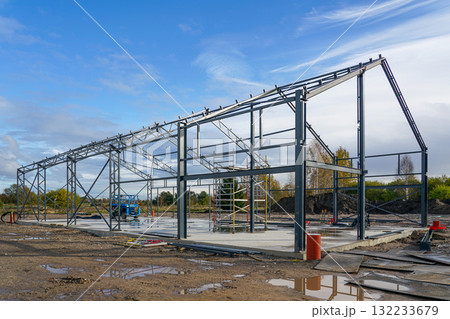 Steel structure framework of industrial warehouse building under construction on a clear blue day Steel structure framework of industrial warehouse building under construction on a clear blue day 132233679