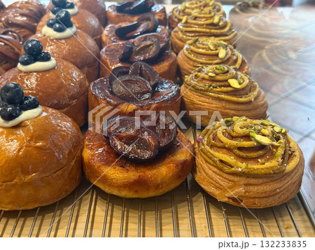 Assorted pastries with blueberries, plums, and pistachios in bakery display. Sweetness, texture, and craftsmanship in artisanal dessert presentation. Assorted pastries with blueberries, plums, and pistachios in bakery display. Sweetness, texture, and craftsmanship in artisanal dessert presentation. 132233835