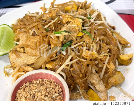 Traditional Thai Pad Thai noodles with chicken, egg, bean sprouts, lime, crushed peanuts. Asian street food concept. Traditional Thai Pad Thai noodles with chicken, egg, bean sprouts, lime, crushed peanuts. Asian street food concept. 132233971