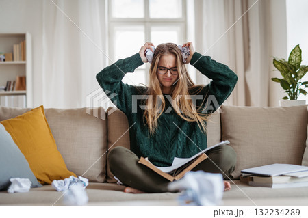 Young female student feeling hopeless during study session at dorm. 132234289