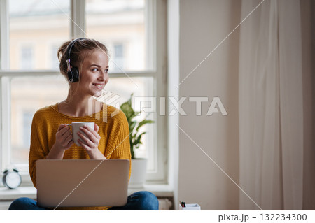 Young female student with headphones sitting at the table and studying. Young female student with headphones sitting at the table and studying. 132234300