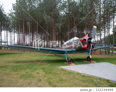 silver propeller trainer with red nose, parked on pedestals with three blade prop, chocks and blue stands, pine tree backdrop, classic lines, static museum setting for heritage display silver propeller trainer with red nose, parked on pedestals with three blade prop, chocks and blue stands, pine tree backdrop, classic lines, static museum setting for heritage display 132234494