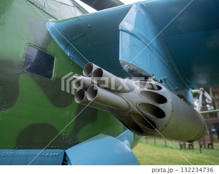 closeup of rocket tubes mounted on camouflaged fuselage emphasizes circular openings and chipped paint, low angle shows mounting rack and grassy display setting, evocative of military 132234736