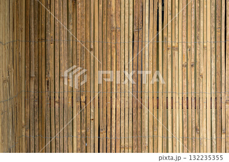 Vertical bamboo fence tied with wire, showing natural color variations and rustic detail. Concept of eco materials, privacy barrier, sustainable construction. Copy space 132235355