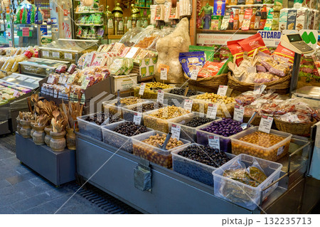 A bustling market scene showcasing a vibrant array of olives and other foods. Baskets and containers overflow with fresh produce and goods. A bustling market scene showcasing a vibrant array of olives and other foods. Baskets and containers overflow with fresh produce and goods. 132235713