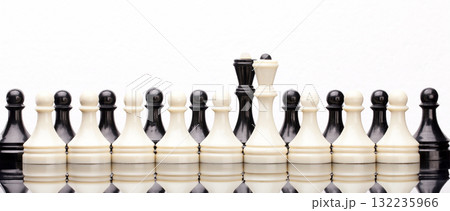 Symmetrical lineup of white and black chess pieces on reflective surface, symbolizing strategy, balance and competition. Symmetrical lineup of white and black chess pieces on reflective surface, symbolizing strategy, balance and competition. 132235966