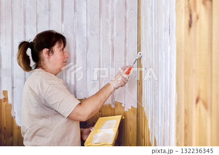 Painter is carefully applying white paint to wooden surface, ensuring smooth finish. Painter is carefully applying white paint to wooden surface, ensuring smooth finish. 132236345