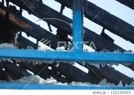 A blue roof with black shingles and a broken window 132238503