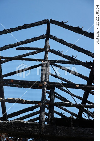 A black and charred roof with a blue sky in the background A black and charred roof with a blue sky in the background 132238564