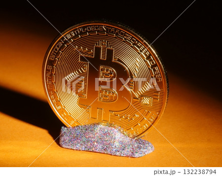 A gold coin with the letter B on it is sitting on a piece of glitter 132238794