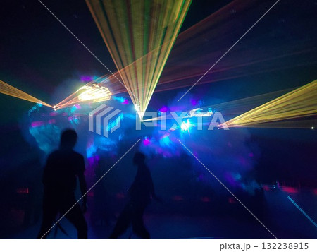 Group of people are walking through a dark room with colorful lights 132238915