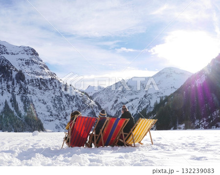 Group of people are sitting on chairs in the snow Group of people are sitting on chairs in the snow 132239083