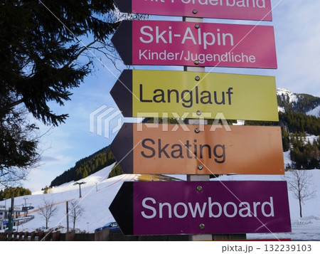 Signboard with a row of arrows pointing to different activities such as skiing 132239103