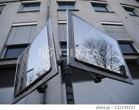 Two mirrors are mounted on a pole in front of a building Two mirrors are mounted on a pole in front of a building 132239122