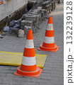 Two orange and white traffic cones are on a brick sidewalk 132239128