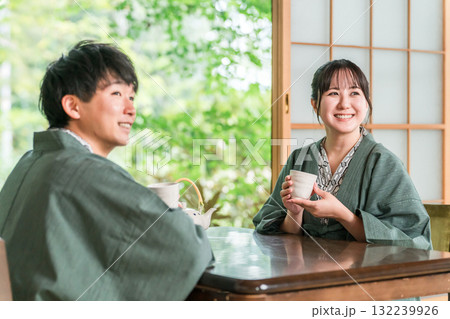 庭の景色が見える旅館の和室でお茶を飲む浴衣姿のカップル,夫婦 132239926
