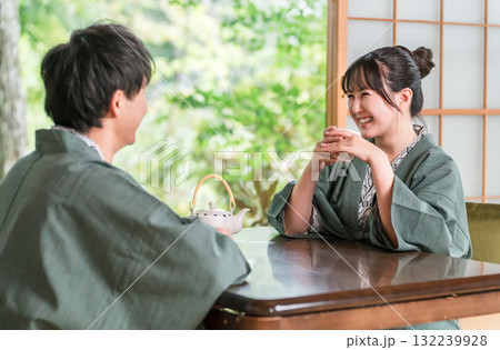 庭の景色が見える旅館の和室でお茶を飲む浴衣姿のカップル,夫婦 132239928