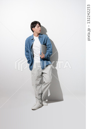 デニムでパソコンを持つ若い男性　エンジニアやデザイナー、フリーランスのイメージの全身	 132242253