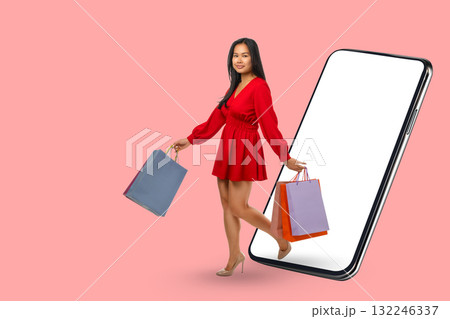 A woman is engaged in online shopping while holding bags A woman is engaged in online shopping while holding bags 132246337