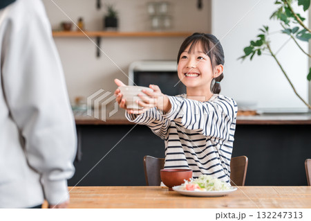 ご飯のおかわりをする元気な女の子 132247313