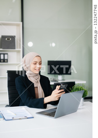 Young Muslim woman working with laptop and tablet Young Muslim woman working with laptop and tablet 132247748