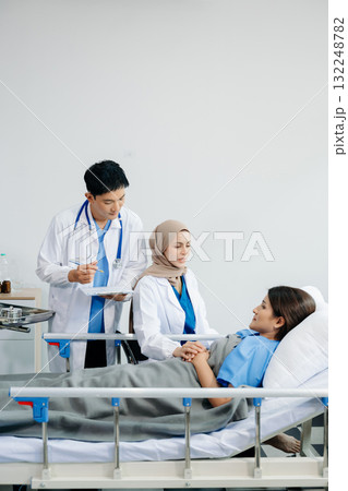 Doctors providing attentive care to a patient in a hospital bed. Compassion, professionalism, and expert healthcare. Ideal for medical Doctors providing attentive care to a patient in a hospital bed. Compassion, professionalism, and expert healthcare. Ideal for medical 132248782