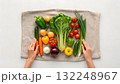 Fresh vegetables arranged on a cloth with hands preparing for cooking in a kitchen 132248967