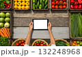 Person using tablet among fresh vegetables and fruits at a market 132248968
