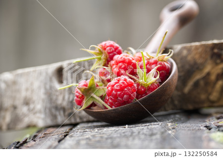 Close up shows ripe, juicy raspberries nestled in a wooden spoon, ready to be enjoyed Close up shows ripe, juicy raspberries nestled in a wooden spoon, ready to be enjoyed 132250584