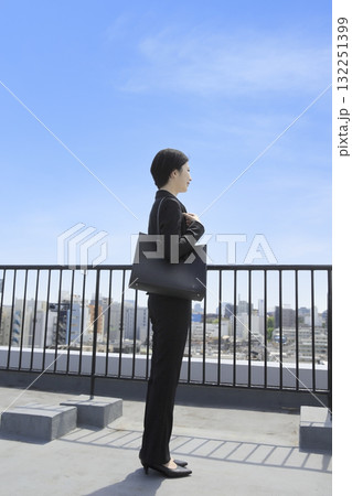 青空の下で街並みを眺める若いビジネスウーマン 青空の下で街並みを眺める若いビジネスウーマン 132251399