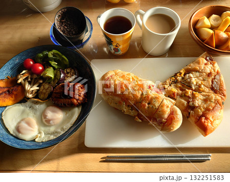 朝の光の中で食べる洋風な朝食セットの例(総菜パン，ミニ・ピザ・クォーターとメインディッシュの組合せ 132251583