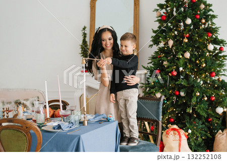 Mother and Son Lighting Candle by Christmas Tree Mother and Son Lighting Candle by Christmas Tree 132252108