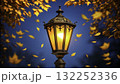 Bright lamp glowing in a serene autumn evening as golden leaves swirl in the gentle breeze 132252336